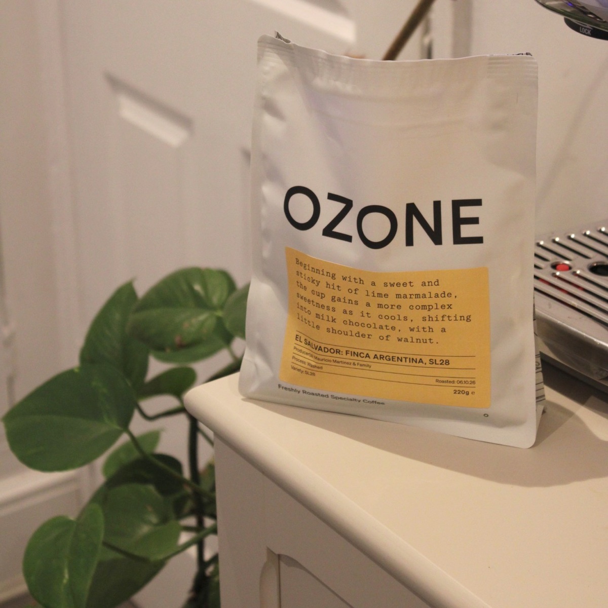 A bag of Ozone El Salvador Finca Argentina SL28 on a kitchen counter beside an espresso machine